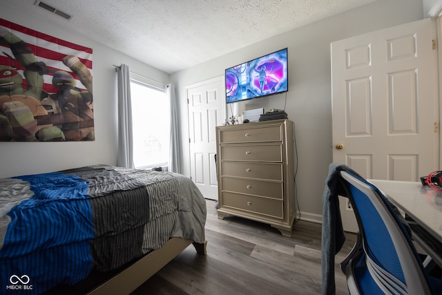 bedroom with a textured ceiling and wood-type flooring