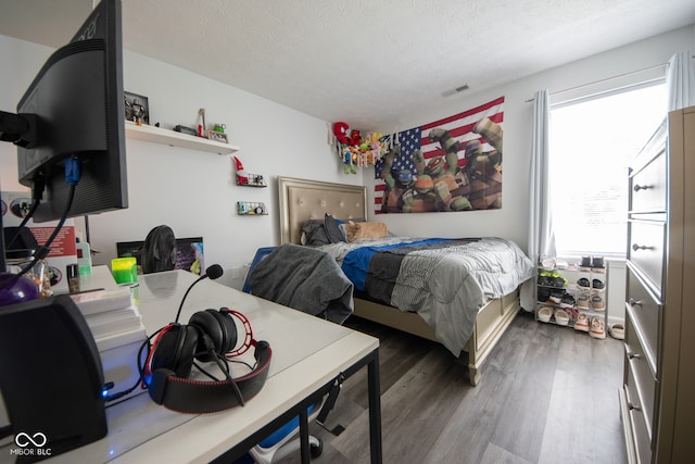 bedroom with dark wood-type flooring, a textured ceiling, and multiple windows