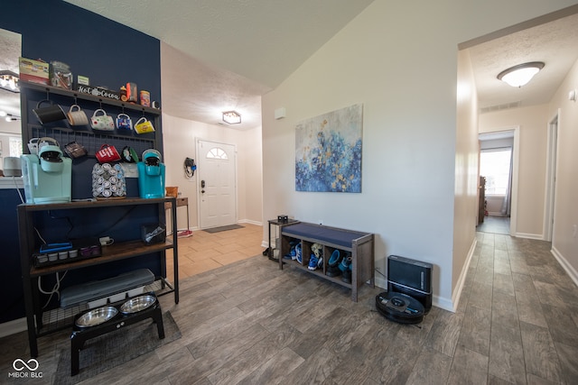 entrance foyer featuring a textured ceiling, vaulted ceiling, and hardwood / wood-style flooring