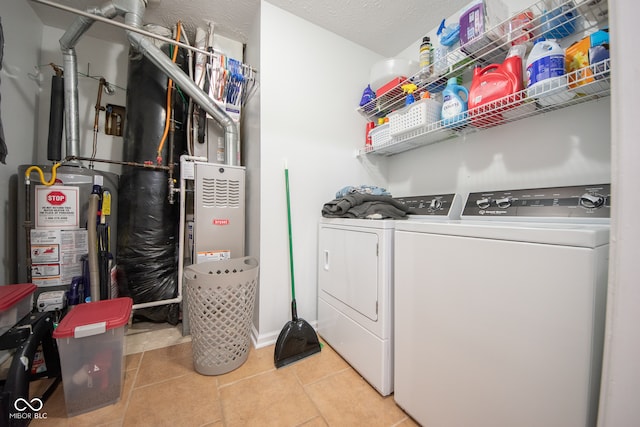 laundry area with a textured ceiling, washing machine and dryer, and light tile patterned floors