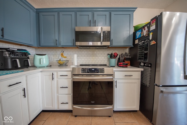 kitchen with blue cabinetry, light tile patterned flooring, and stainless steel appliances