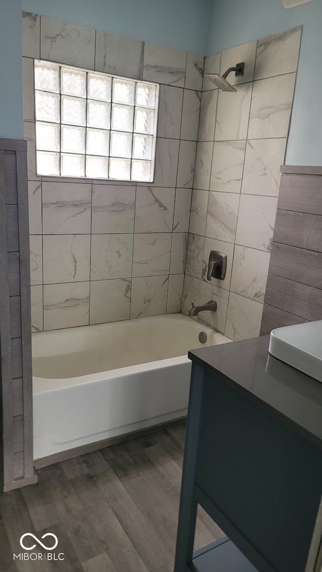 bathroom with hardwood / wood-style floors, tiled shower / bath combo, and vanity