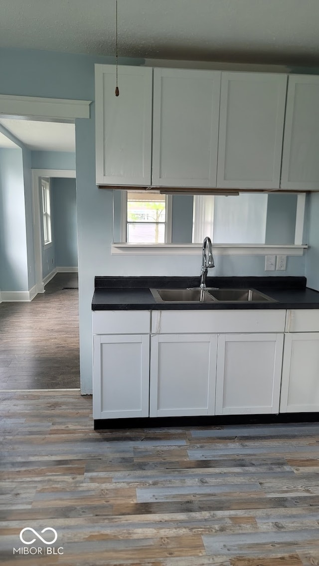 kitchen featuring white cabinetry, sink, and wood-type flooring