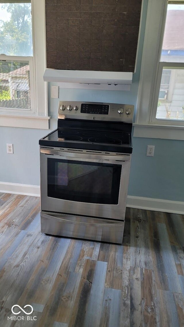 kitchen featuring hardwood / wood-style floors, stainless steel electric range, and wall chimney range hood