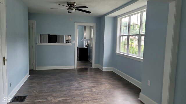 empty room featuring a textured ceiling, ceiling fan, and dark hardwood / wood-style floors