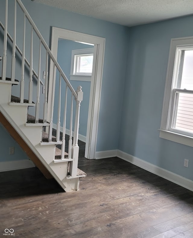 stairway featuring a textured ceiling and wood-type flooring