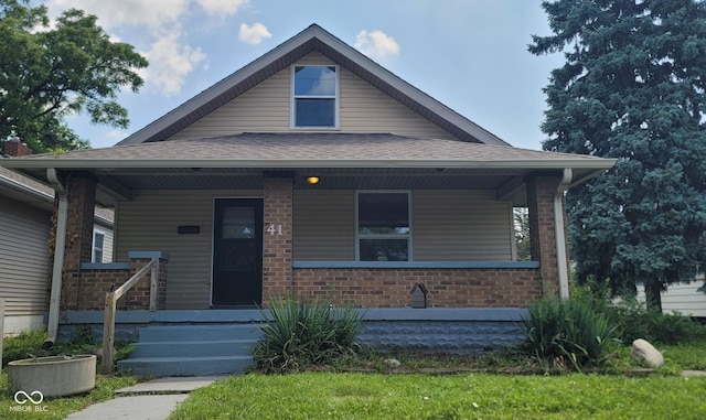 bungalow-style home featuring a porch, a shingled roof, and brick siding