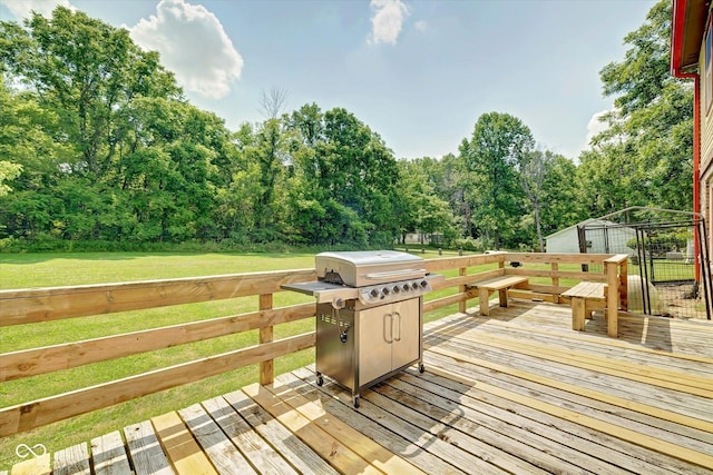 wooden deck featuring a yard and a grill