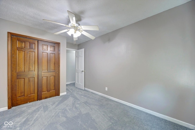 unfurnished bedroom with ceiling fan, a closet, light colored carpet, and a textured ceiling