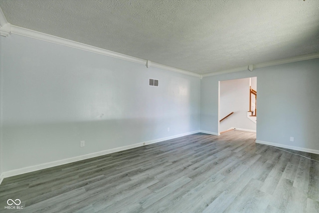 spare room with wood-type flooring, a textured ceiling, and ornamental molding