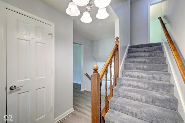 stairs featuring hardwood / wood-style flooring and an inviting chandelier