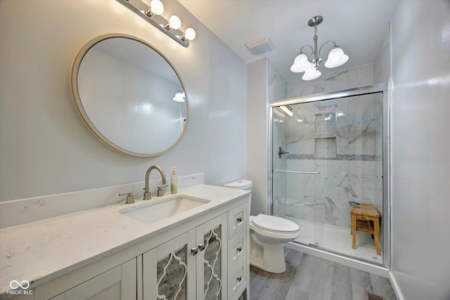 bathroom with a notable chandelier, wood-type flooring, an enclosed shower, toilet, and vanity