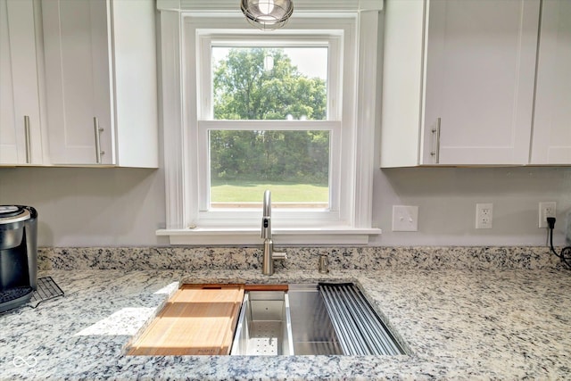 room details featuring white cabinets and light stone countertops