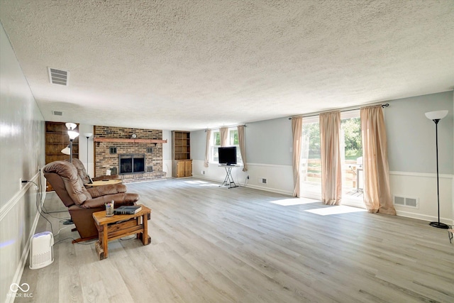 living room featuring a textured ceiling, light hardwood / wood-style floors, and a fireplace