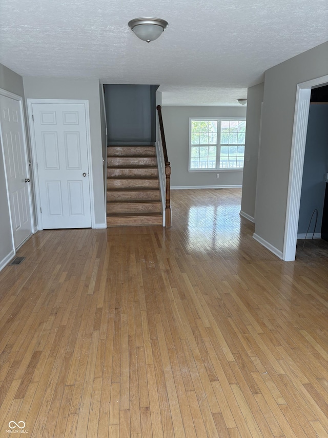 unfurnished room featuring a textured ceiling and light wood-type flooring