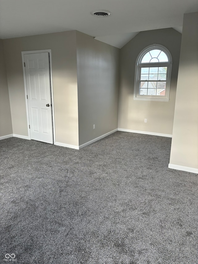 carpeted empty room featuring lofted ceiling