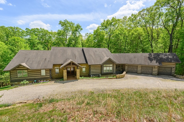 view of front facade featuring log exterior, a garage, driveway, and roof with shingles