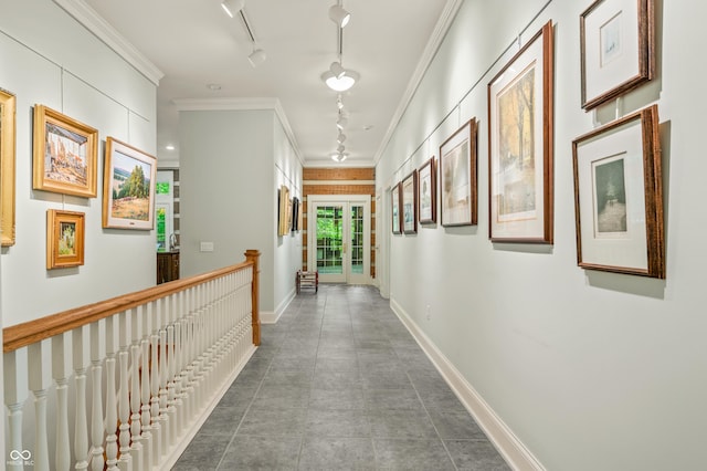 hall with baseboards, an upstairs landing, ornamental molding, and rail lighting