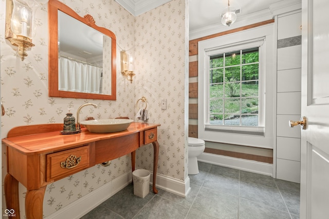 full bathroom featuring a healthy amount of sunlight, toilet, wallpapered walls, and baseboards