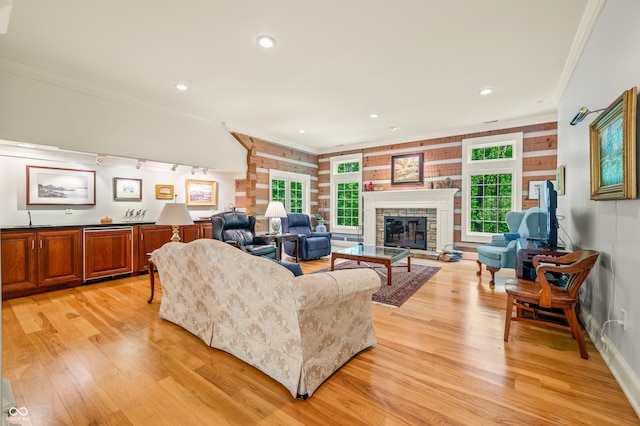 living room featuring a fireplace, crown molding, light wood-type flooring, and a healthy amount of sunlight