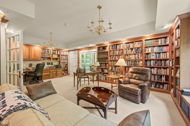 living area with a notable chandelier, built in desk, lofted ceiling, light colored carpet, and wall of books