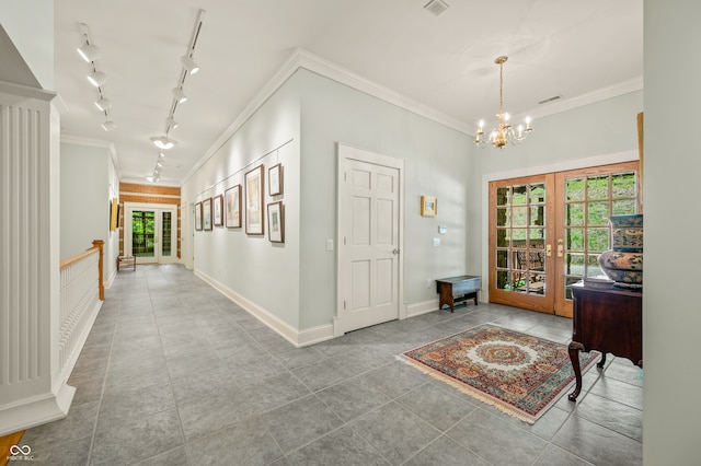 tiled foyer entrance featuring crown molding, french doors, track lighting, and a notable chandelier