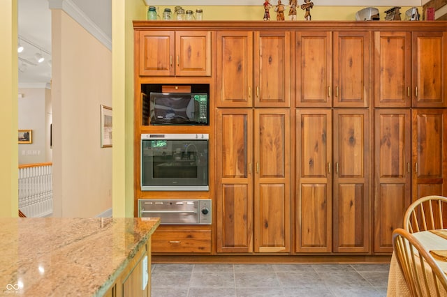 kitchen with oven, crown molding, black microwave, light stone countertops, and brown cabinets