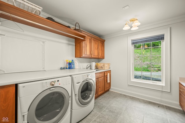 washroom featuring light tile patterned floors, baseboards, cabinet space, crown molding, and washer and clothes dryer