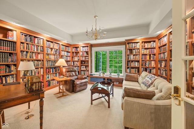 sitting room with a notable chandelier, carpet flooring, and bookshelves