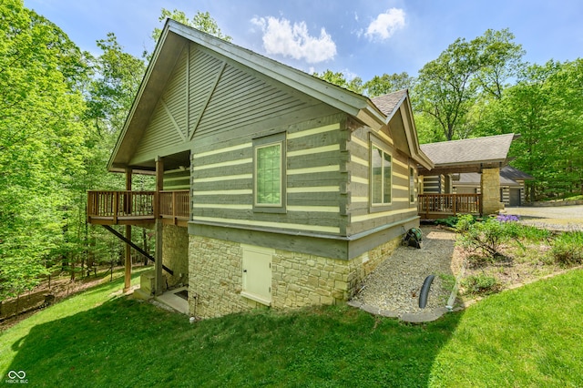 view of side of property with a lawn, a wooden deck, and a shingled roof