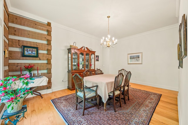 dining area featuring an inviting chandelier, wood finished floors, baseboards, and ornamental molding