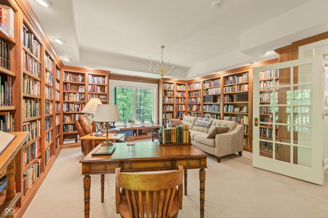 interior space with a raised ceiling, light colored carpet, and an inviting chandelier