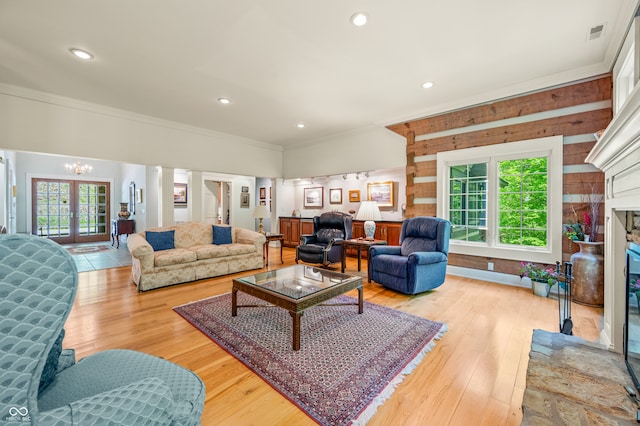 living room with light hardwood / wood-style floors, french doors, wood walls, and crown molding