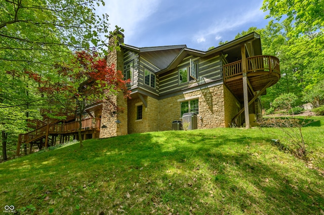 view of home's exterior with a lawn, central AC unit, a chimney, a deck, and stone siding