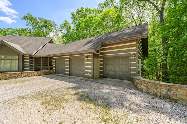 exterior space featuring a garage, driveway, and a shingled roof