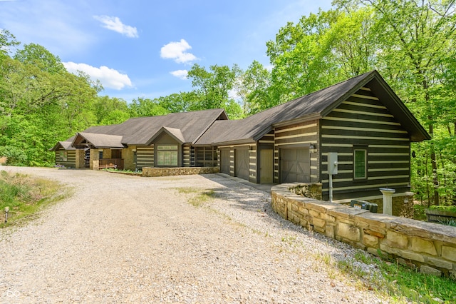 cabin with gravel driveway and an attached garage