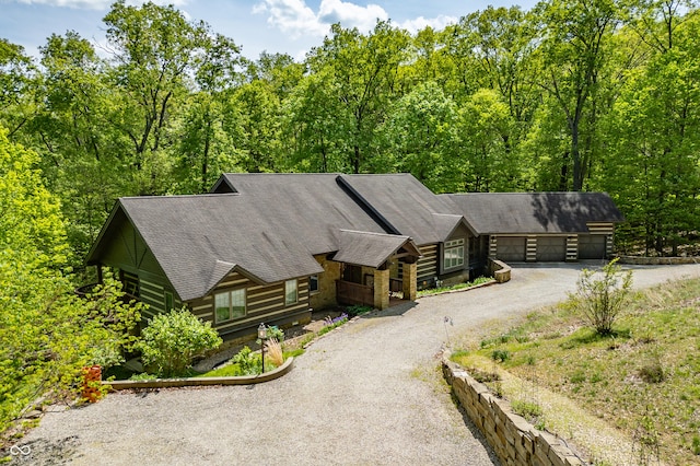 log cabin featuring a view of trees, a garage, and driveway