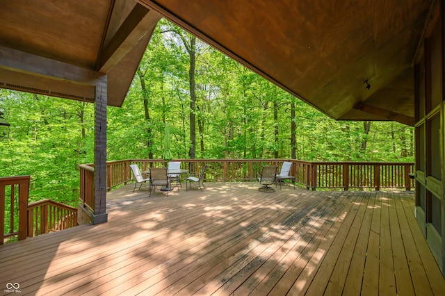 wooden deck featuring outdoor dining area and a wooded view