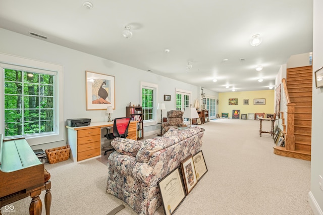 living area featuring visible vents, stairway, and carpet