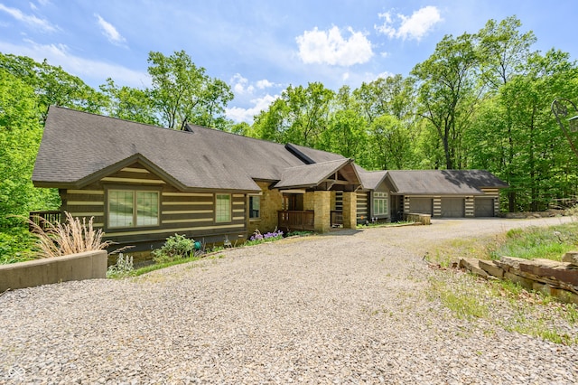 cabin featuring a garage, driveway, and a shingled roof