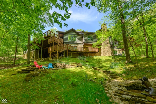 rear view of property featuring a deck and a lawn