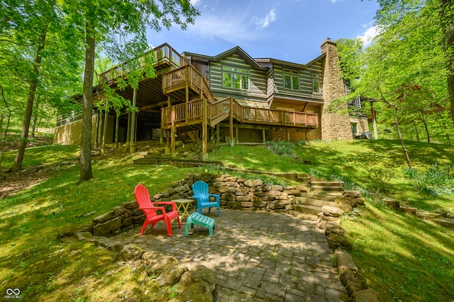 rear view of property featuring an outdoor fire pit, a patio area, a deck, and a lawn