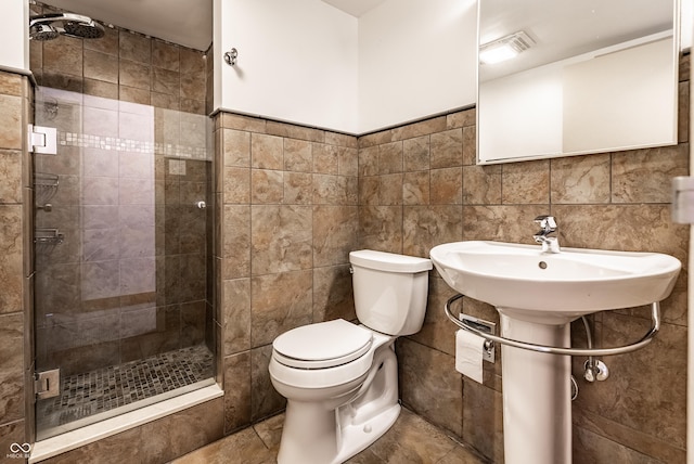 bathroom with tile walls, a shower with door, and toilet