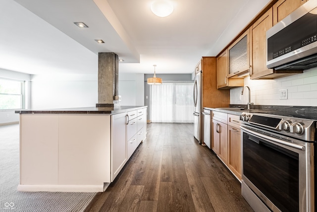 kitchen with sink, appliances with stainless steel finishes, white cabinetry, hanging light fixtures, and decorative backsplash