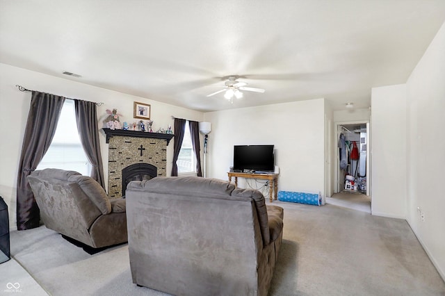 carpeted living room featuring ceiling fan and a wood stove