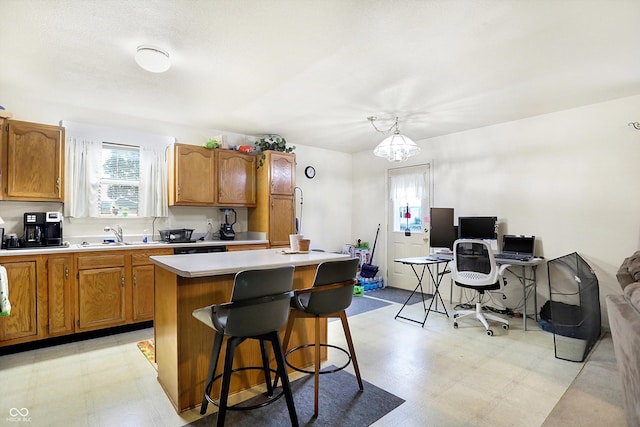 kitchen with a center island, decorative light fixtures, a kitchen bar, sink, and a notable chandelier