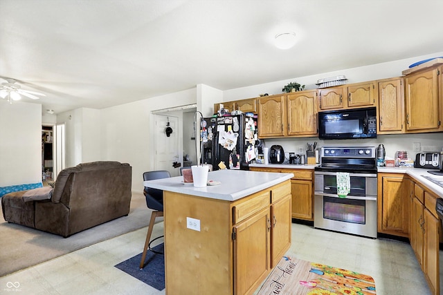 kitchen with black appliances, a breakfast bar, ceiling fan, and a center island