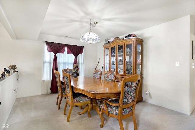 dining room with light colored carpet and a notable chandelier