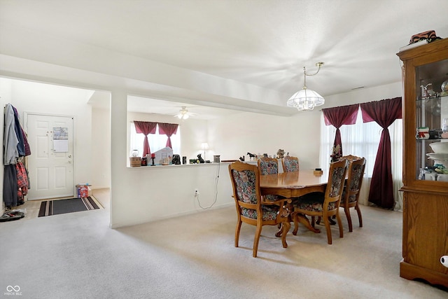 carpeted dining area featuring ceiling fan with notable chandelier