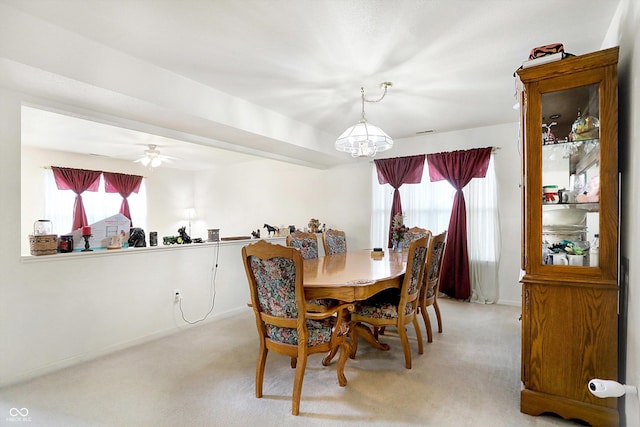 carpeted dining room with ceiling fan with notable chandelier